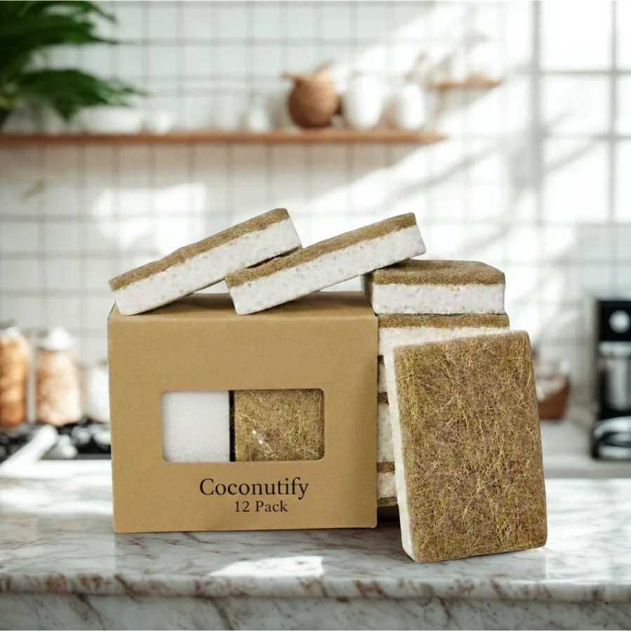 Coconutify coconut-fiber dish scrubber in a clear pot with a wooden-handled brush, beside a halved coconut and palm leaves